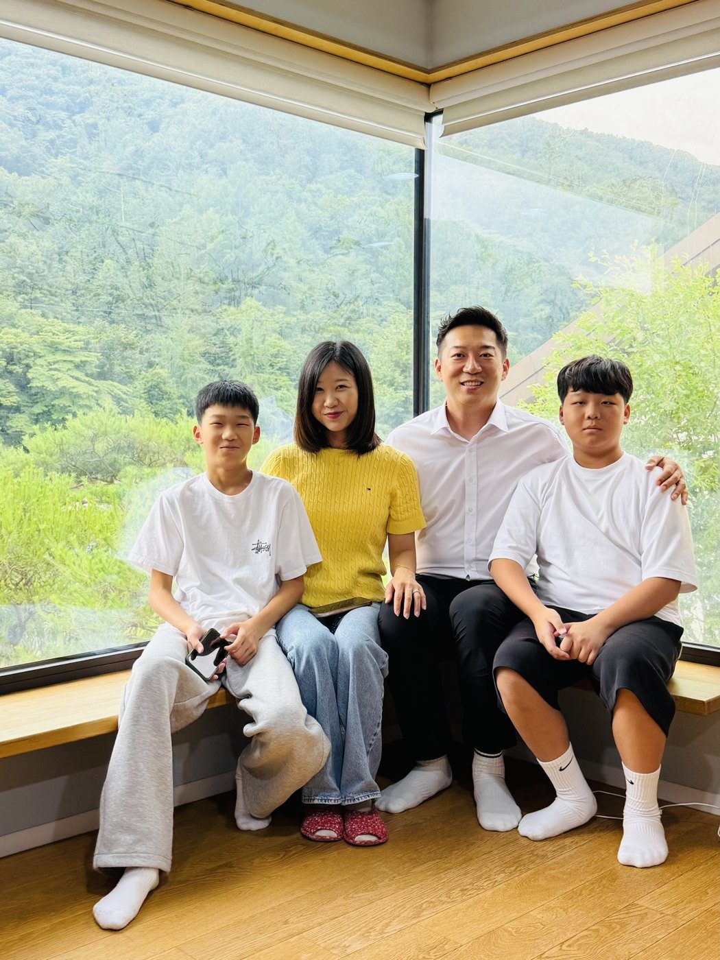 The Ji family of four sitting side by side on a bench by a window